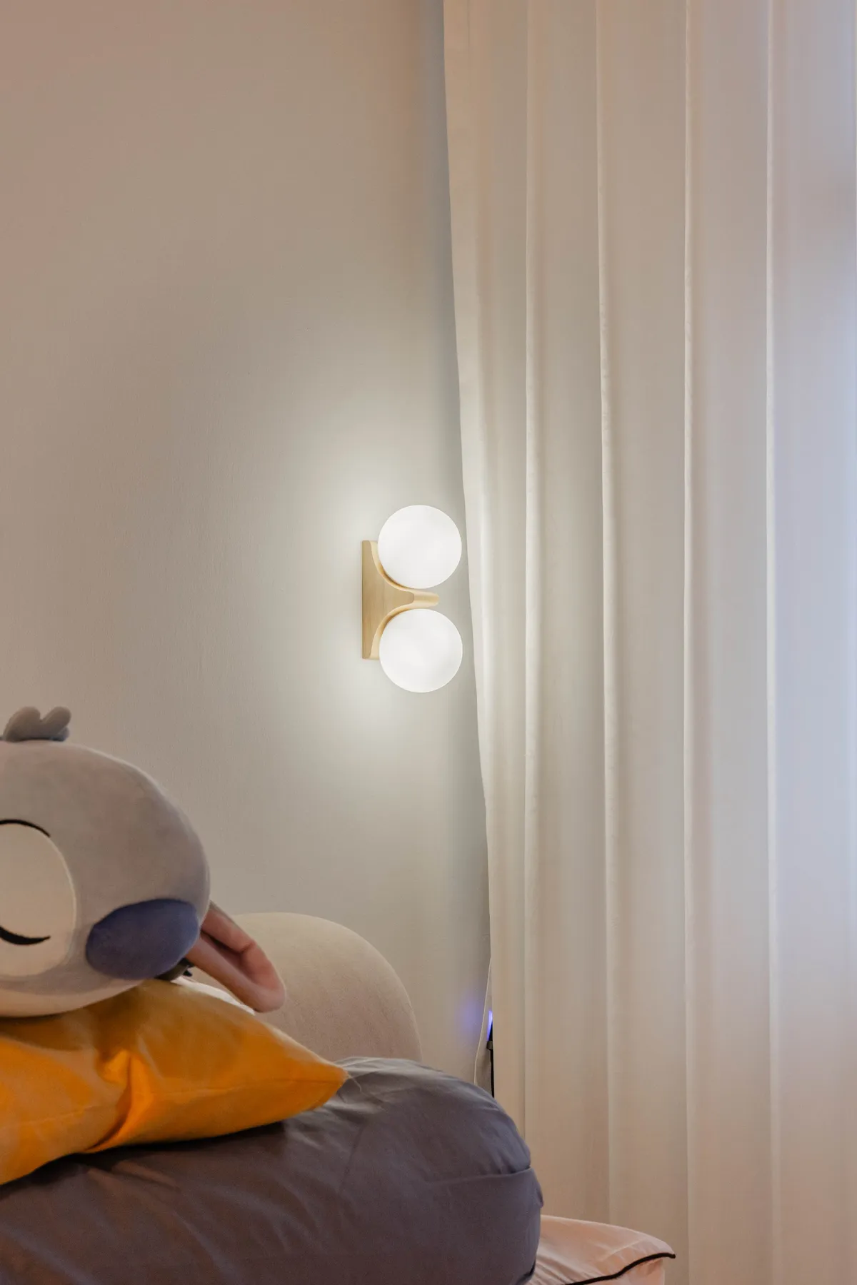 Warm wall sconce beside sheer curtains